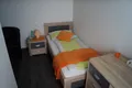 Einzelzimmer mit Bett, Nachttisch und oranger Decke