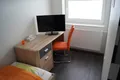 Schreibtisch mit Fernseher und orangem Stuhl im Einzelzimmer