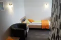 Einzelzimmer mit oranger Tagesdecke und Ledersessel