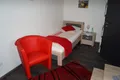 Einzelzimmer mit Bett, Nachttisch und rotem Sessel