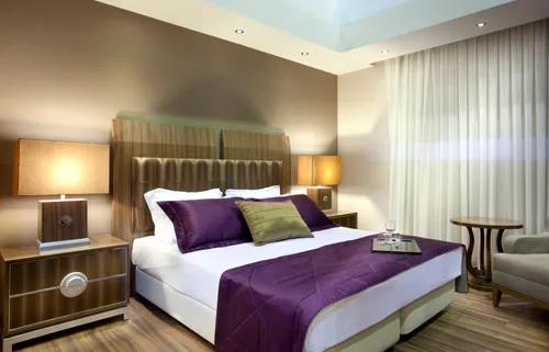 Hotelzimmer mit Doppelbett und lila Tagesdecke